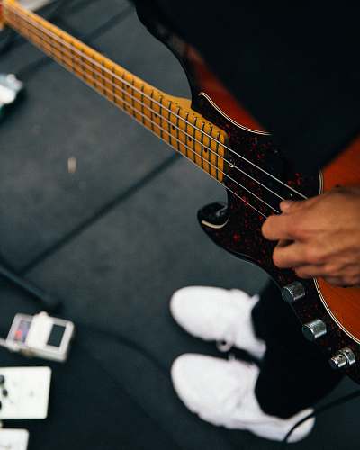 music person playing brown and black bass guitar guitar